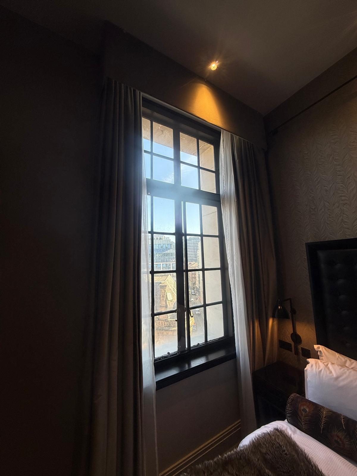 Slim dark-framed aluminium secondary glazing fitted to a tall bedroom window
