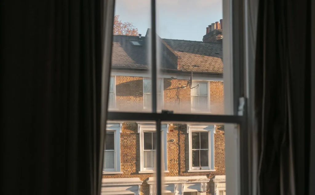 View through a traditional sash window towards a row of Victorian terraced houses