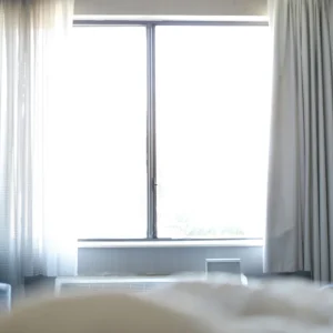 Bright hotel room with a large window and light curtains