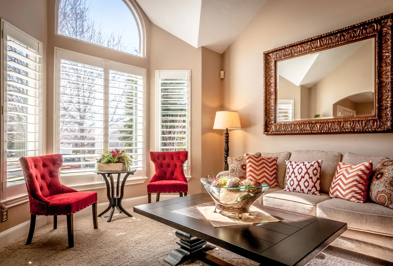 Bright living room with tall bay windows, armchairs and a sofa