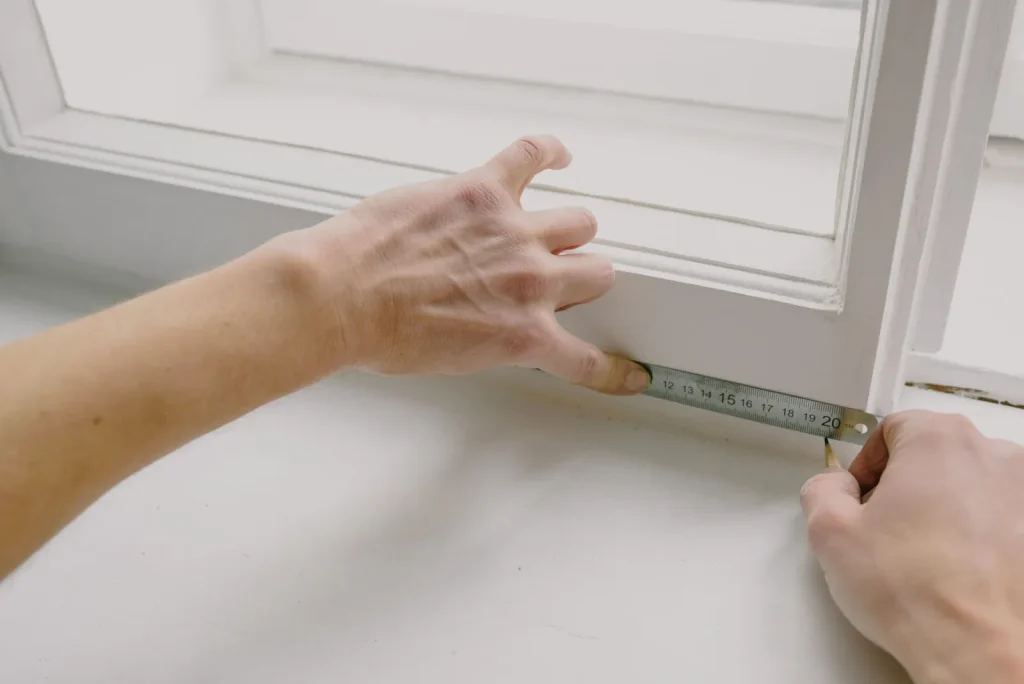 Measuring the inside of a window frame with a tape measure to price secondary glazing
