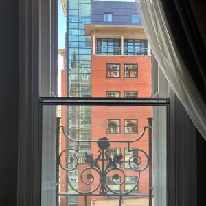White-framed vertical sliding secondary glazing fitted inside a period sash window with a balcony railing